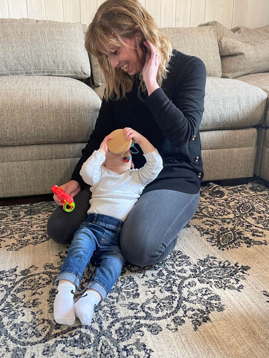 An early intervention specialist smiles as a child in her caseload lays in her lap.