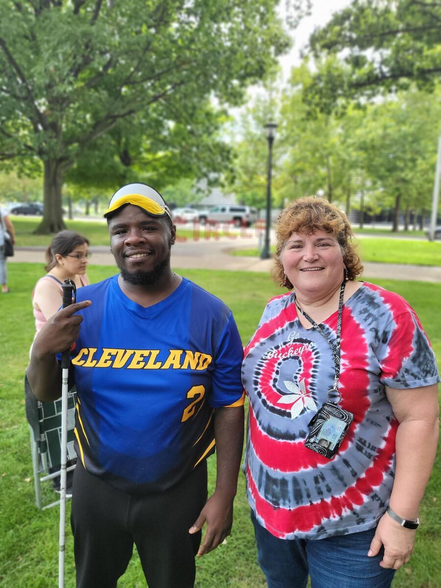 A man in a Cleveland Scrappers jersey and blindfold smiles for a picture with his employment specialist at CSC.