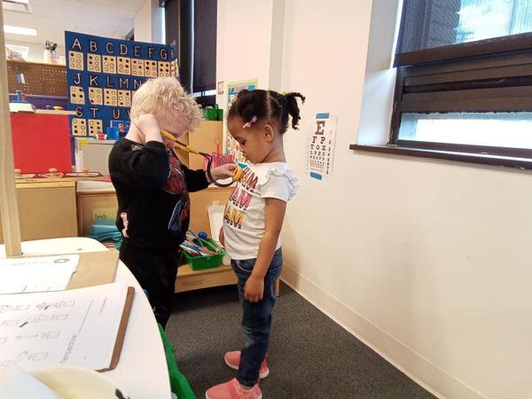 Two preschoolers play with a toy stethoscope and pretend to be a doctors.