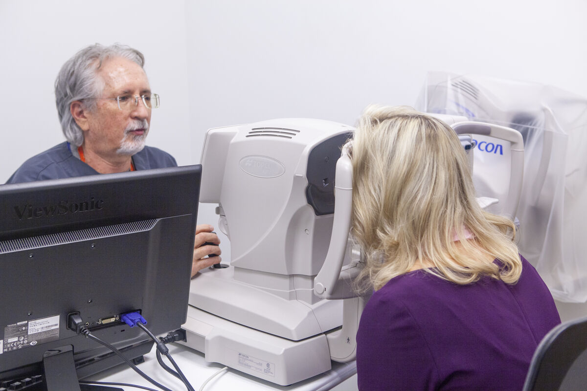 An eye care specialist has a patient look through a medical device to test her vision.