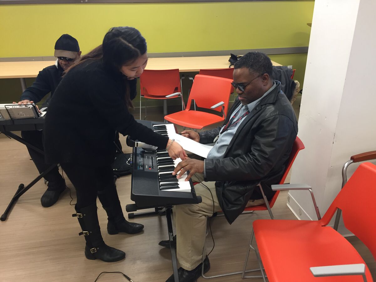 Image of a volunteer teaching a client piano