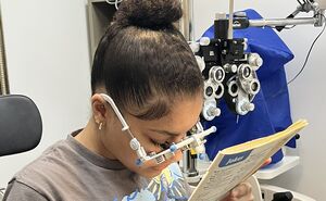 Aaliyah reads a newspaper with test lenses for bioptics.