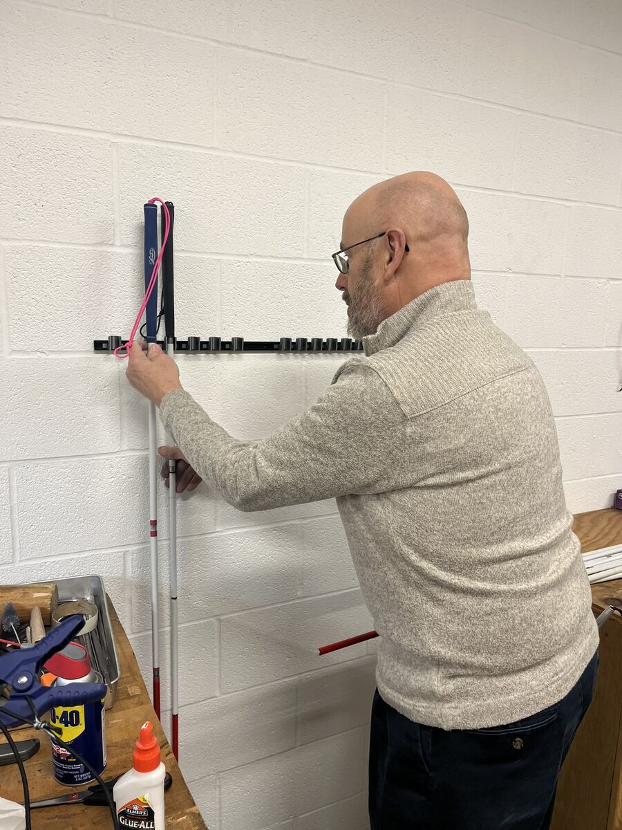 David shows how the new white cane holder he made can hold several white canes at a time.