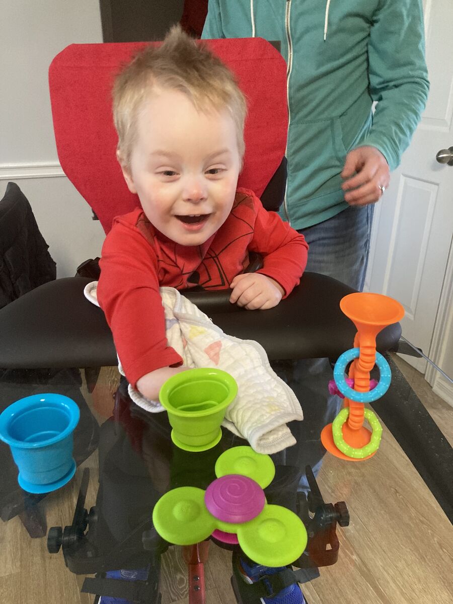 Hayden sits in a chair with toys in front of him