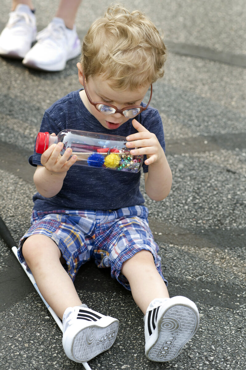 Image of a child sitting next to their white cane