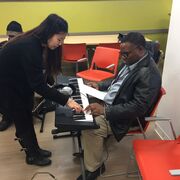 Volunteer helping a client learn to play the keyboard.