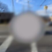 An image of a car from the perspective of someone with severe macular degeneration. The image has a grey spot in the middle, and the peripheral vision is blurred. 