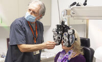 An eye care specialist uses a phoropter in a low vision exam.