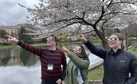 Three people are wearing their eclipse glasses and are excitedly pointing to the sky