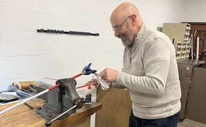David smiles while working on repairing a white cane. 