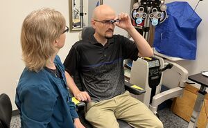 An optometrist helps a patient try out assistive technology in CSC's clinic.