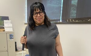Chacity smiles and holds her white cane while wearing her ray ban meta glasses