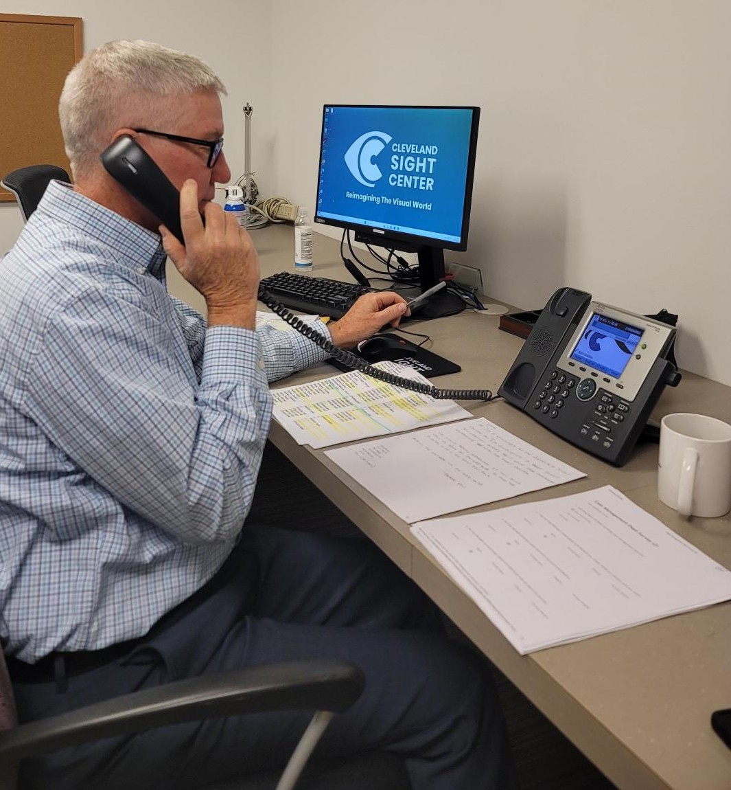 Dave holds up a chorded desk phone as he has three different papers for him to write down survey responses.