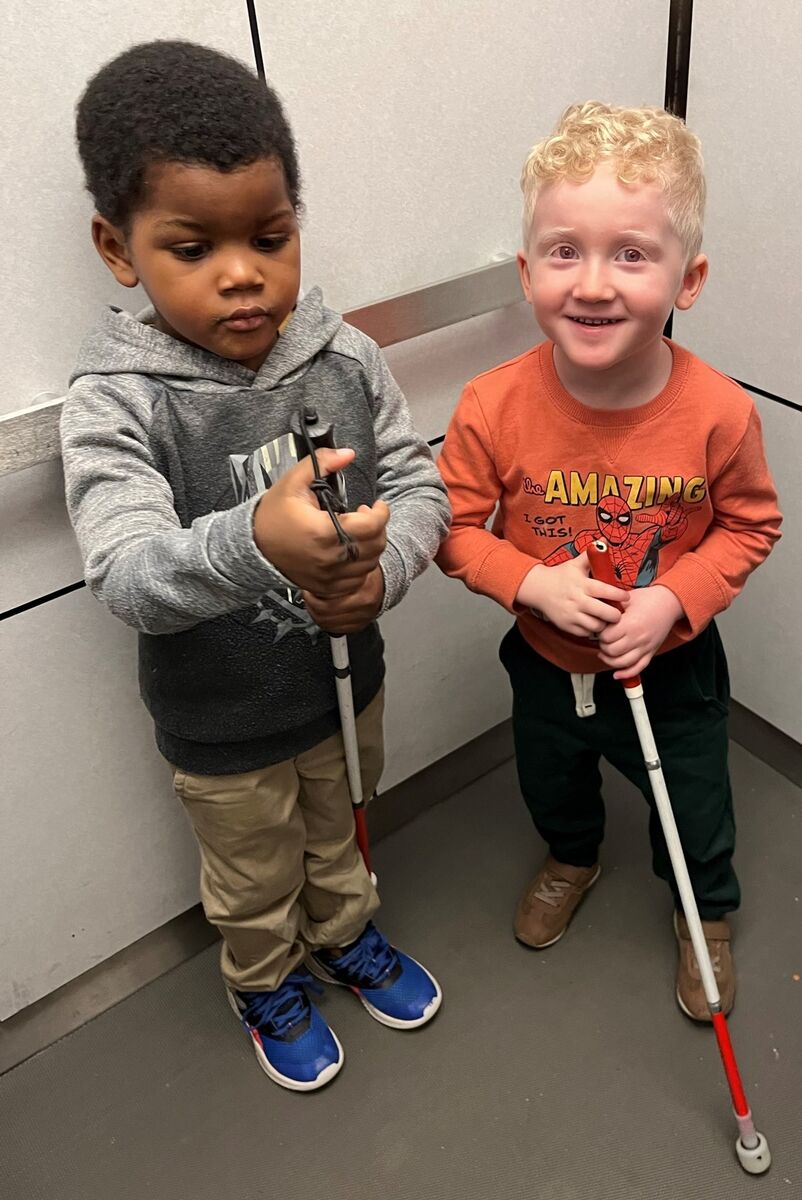 Two preschooler boys hold their white canes and are ready for their orientation and mobility lesson.