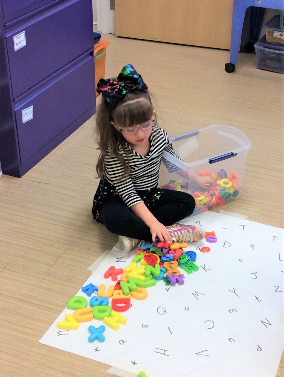 image of a student playing with plastic letters