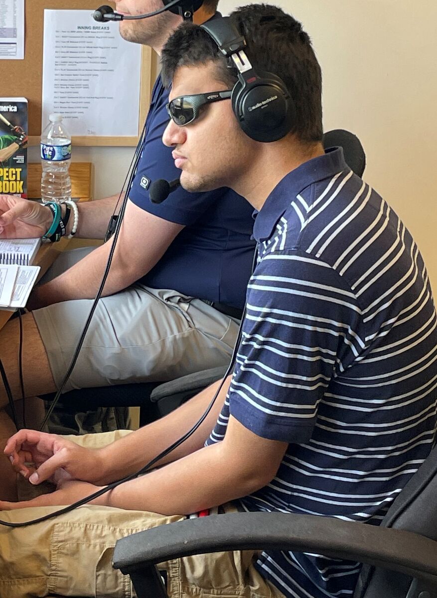 Allan sits in the Lake County Captains' press box next to a coworker, and focuses on the game.
