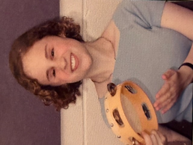Nicole plays a tambourine during a music therapy session.