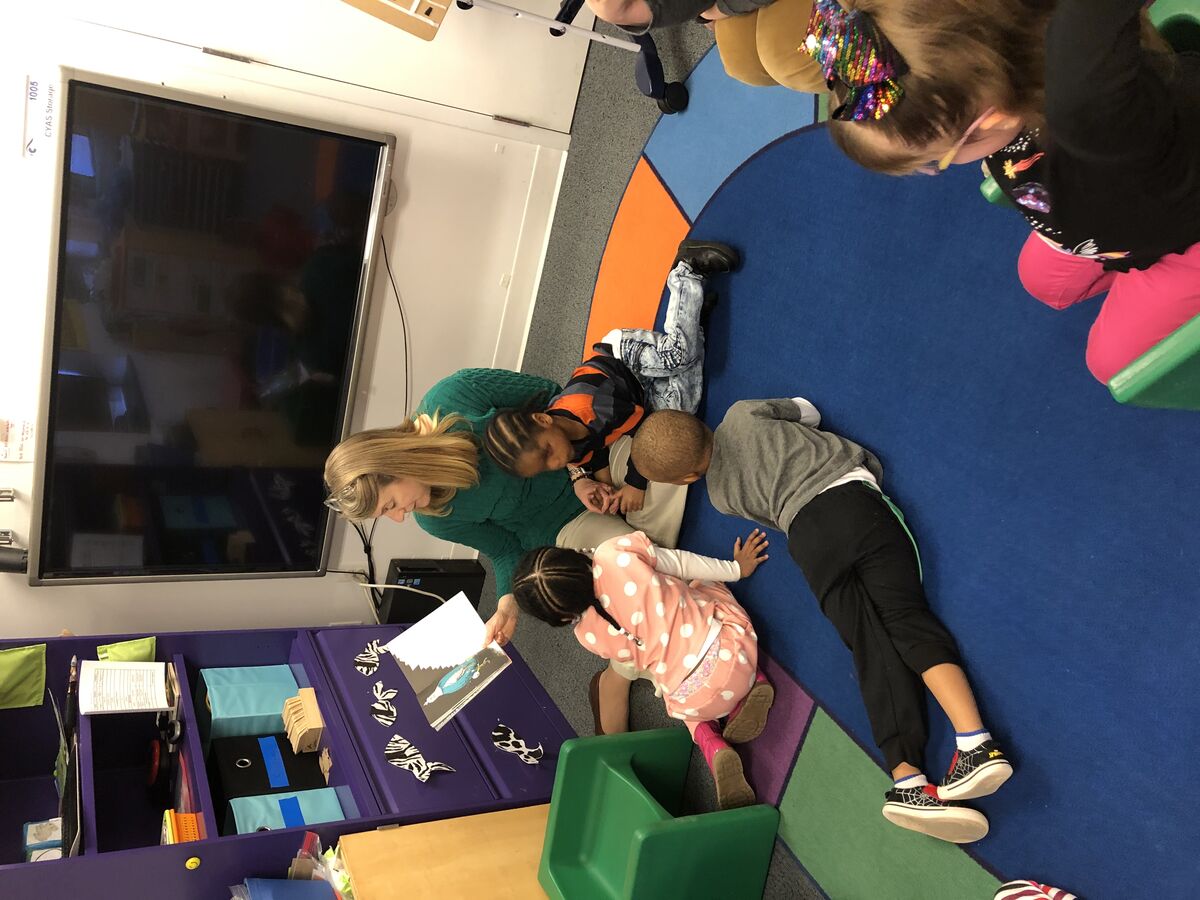 Image of a staff member reading to preschool students