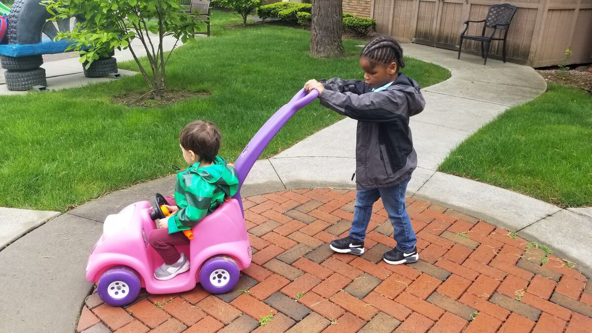 Image of student pushing another in a toy car