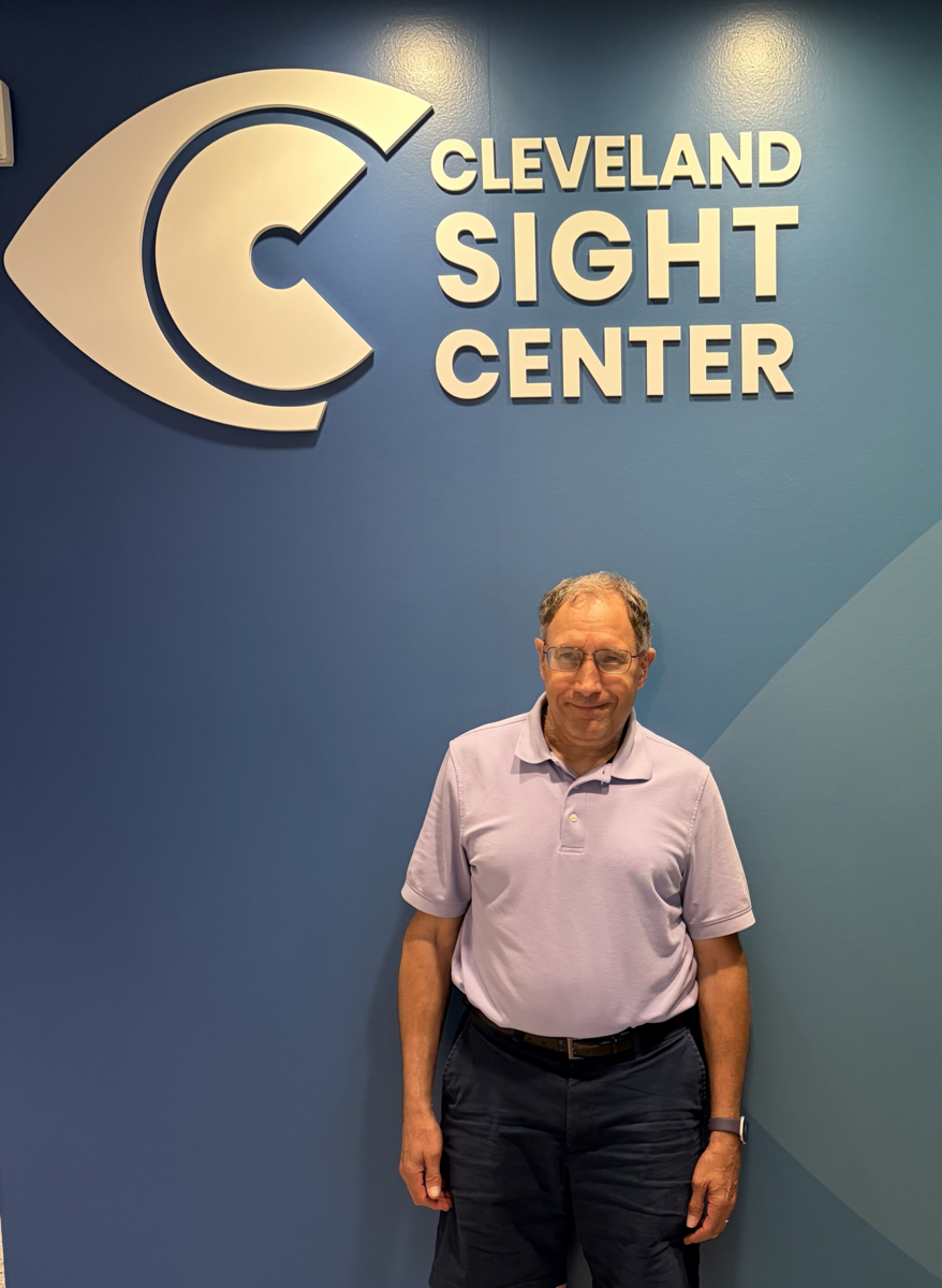 Tom stands by the CSC logo wall in Cleveland Sight Center's lobby.