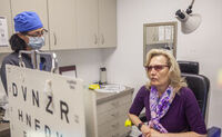 An eye doctor looks at a patient who is reading an eye chart in CSC's clinic.