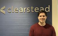 Colin smiles for a photo in front of the Clearstead sign in his office building.