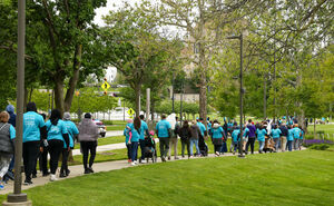 A photo from last White Cane Walk, with most walkers wearing their blue White Cane Walk shirts. They're all making their way down the route by Martin Luther King Jr. blvd.