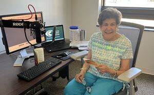 Radio Reader Mary smiles at the camera at the new radio reading recording room.